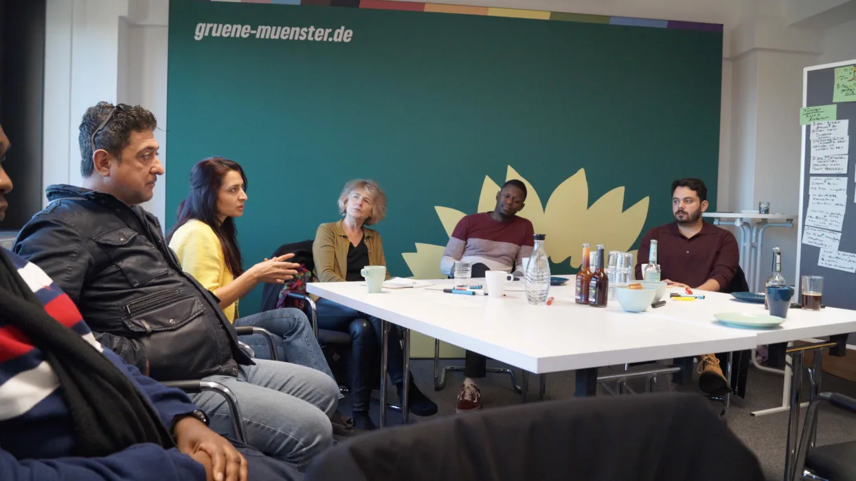 Mehrere Menschen sitzen an einem Tisch und diskutieren miteinander