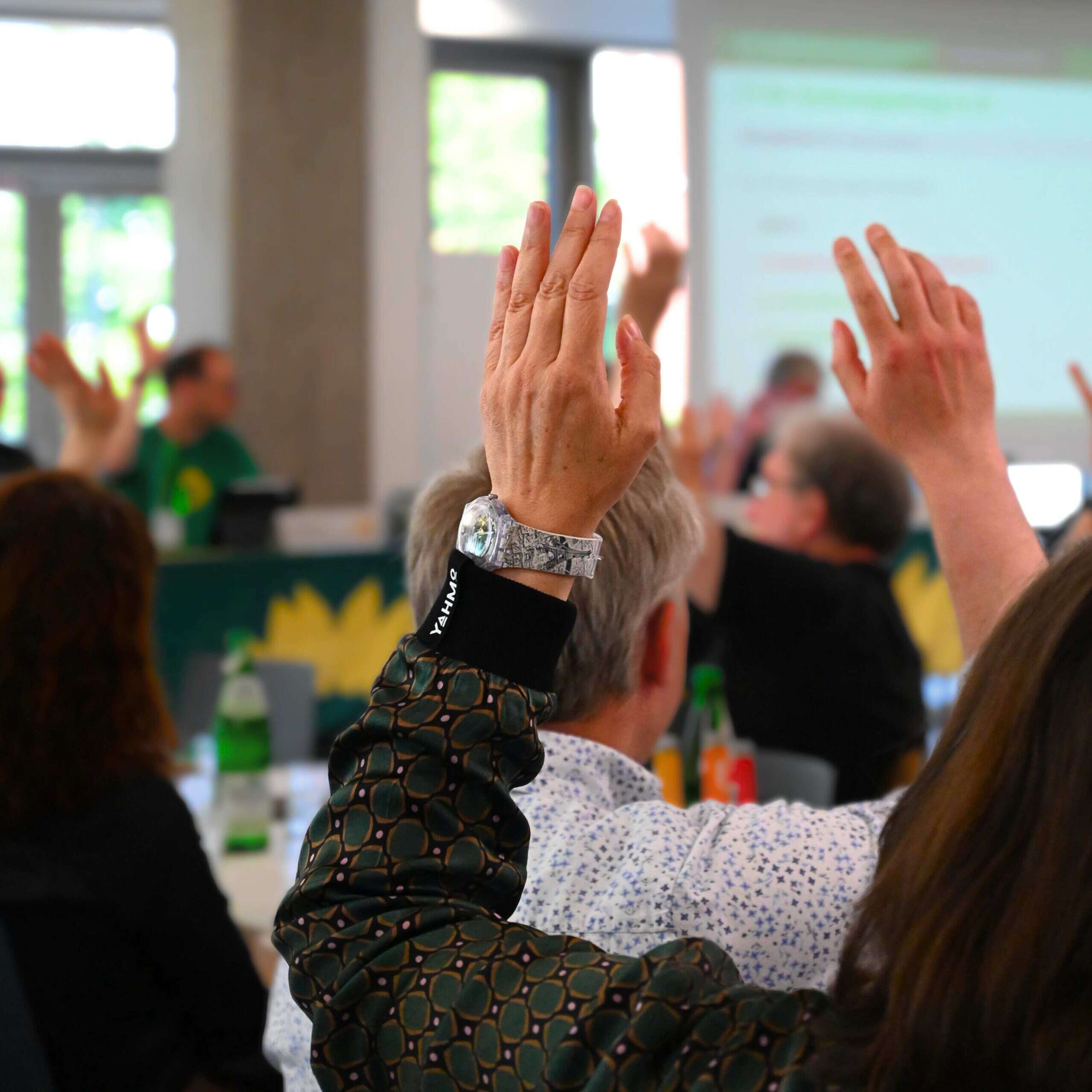 Menschen heben ihre Hand für eine Abstimmung