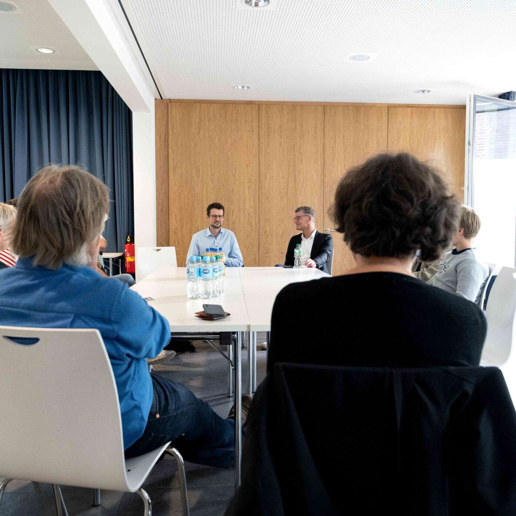 Tilman Fuchs und Severin Solis sitzen an einem Tisch und reden mit Bürger*innen