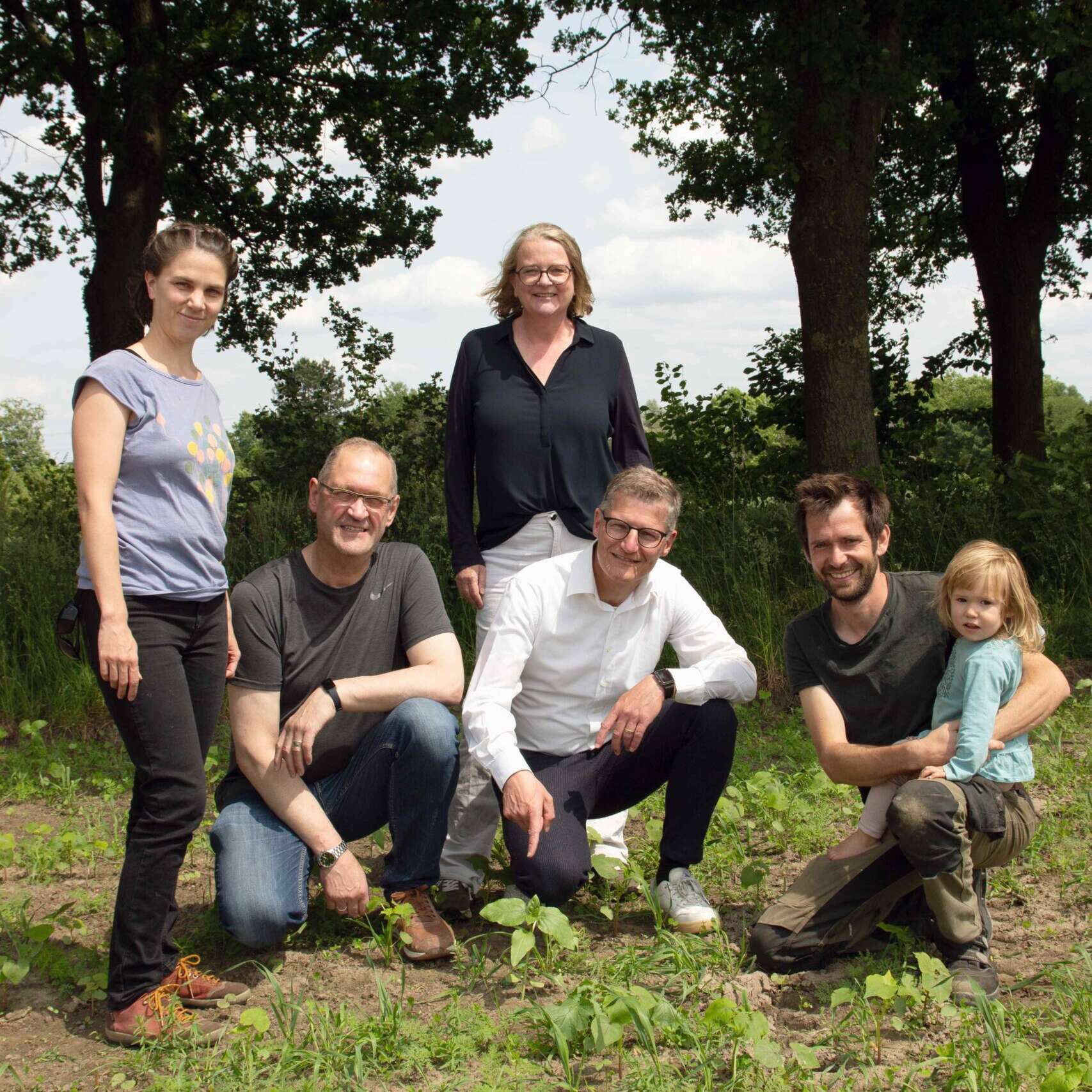 Mehrere Menschen stehen und knien nebeneinander für ein Gruppenfoto