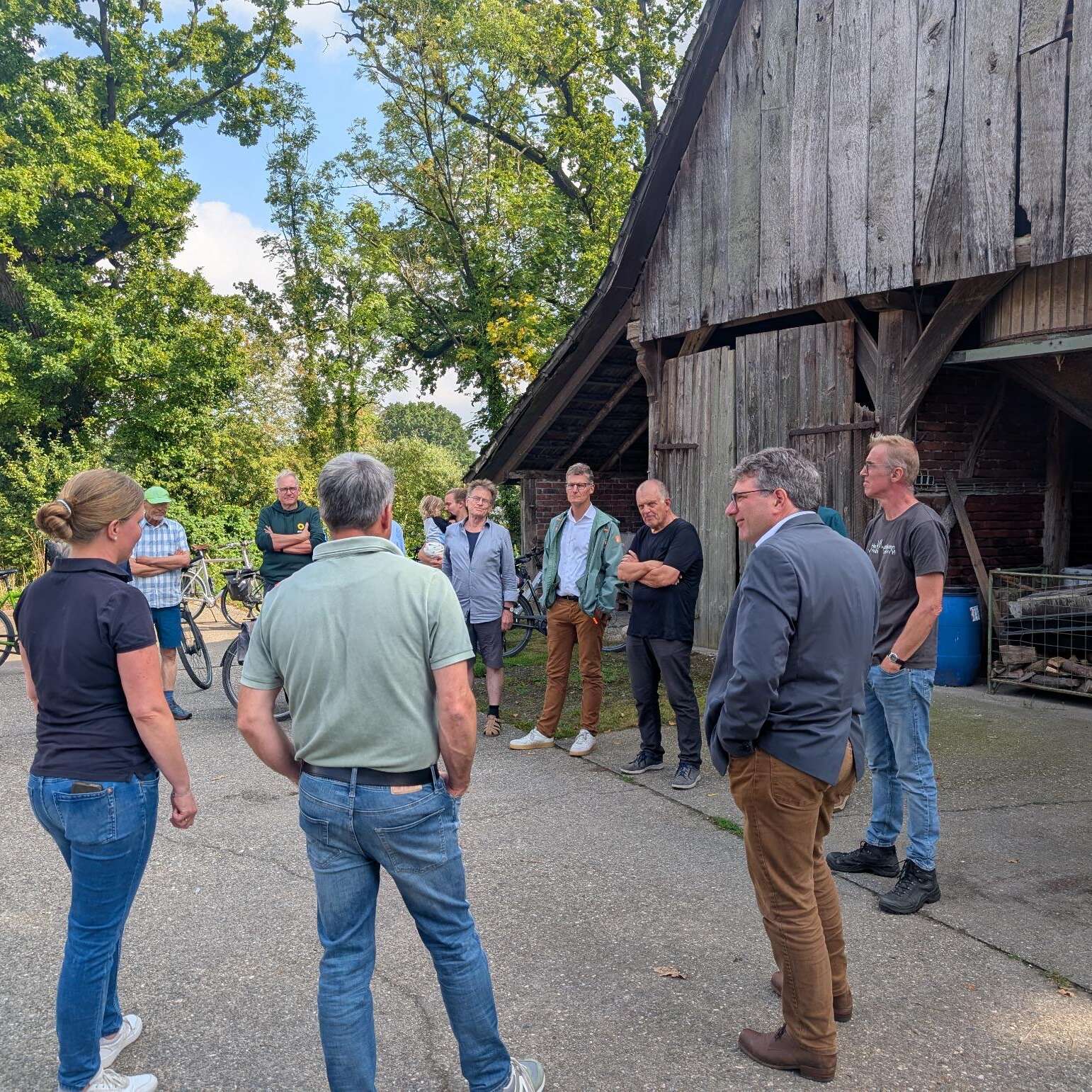 Eine Gruppe von Menschen steht auf einem Bauernhof zusammen und redet